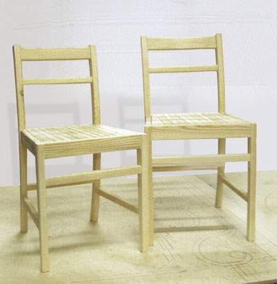 A matching pair of pale coloured wooden chairs