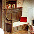 Close-up detail of a stage set - a rustic fireplace with a carved chair in front of it