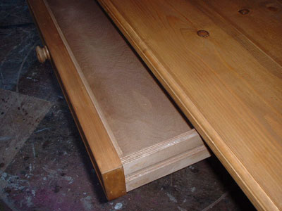 Close up of the open drawer of a large pine table, showing the interior