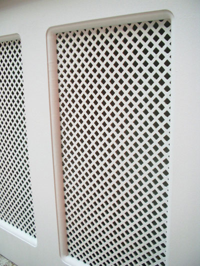 Close-up of the inset mesh panel of a wooden radiator cover, finished in gloss white