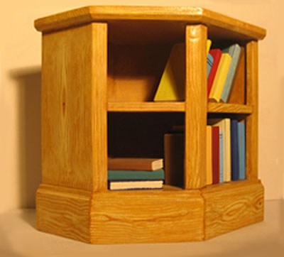 Front view of a wooden, three-sided bookcase with two shelves. Books of various colours are placed on the shelves