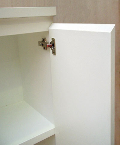 Close up of the top right corner of a white cabinet, the door open to show the silver door fixings